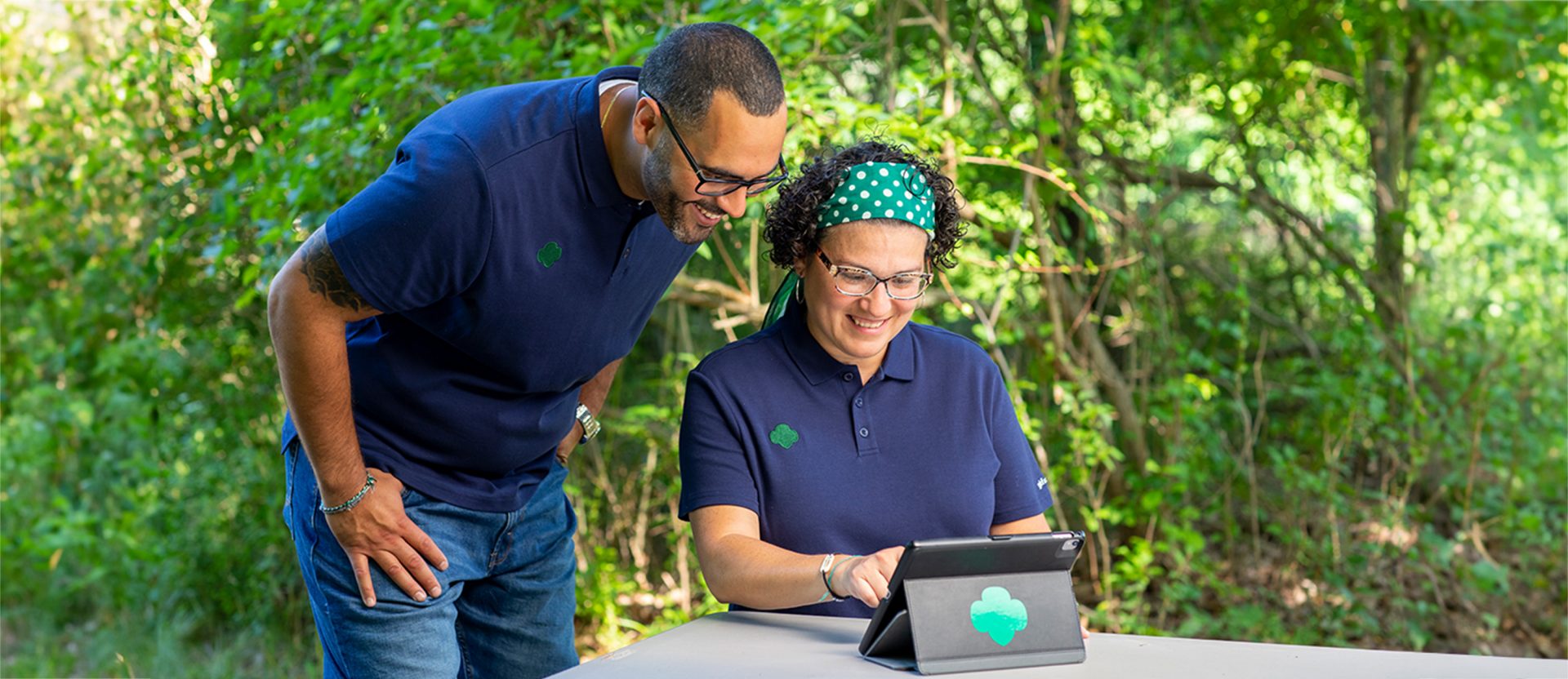 Two volunteers working on a tablet in a park